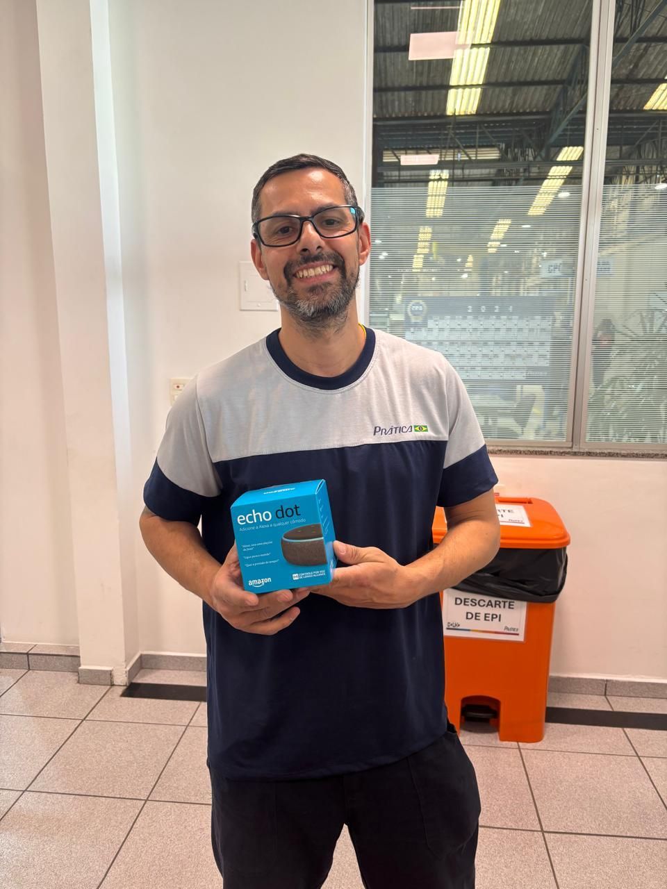 Um homem de camisa azul e branca está segurando uma caixa azul.