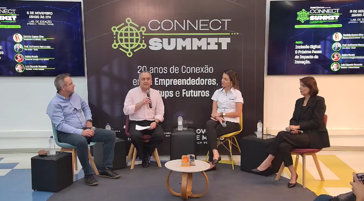 Painel de discussão no evento Connect Summit. Quatro pessoas sentadas em um palco, falando. O logotipo do evento e telas estão visíveis.
