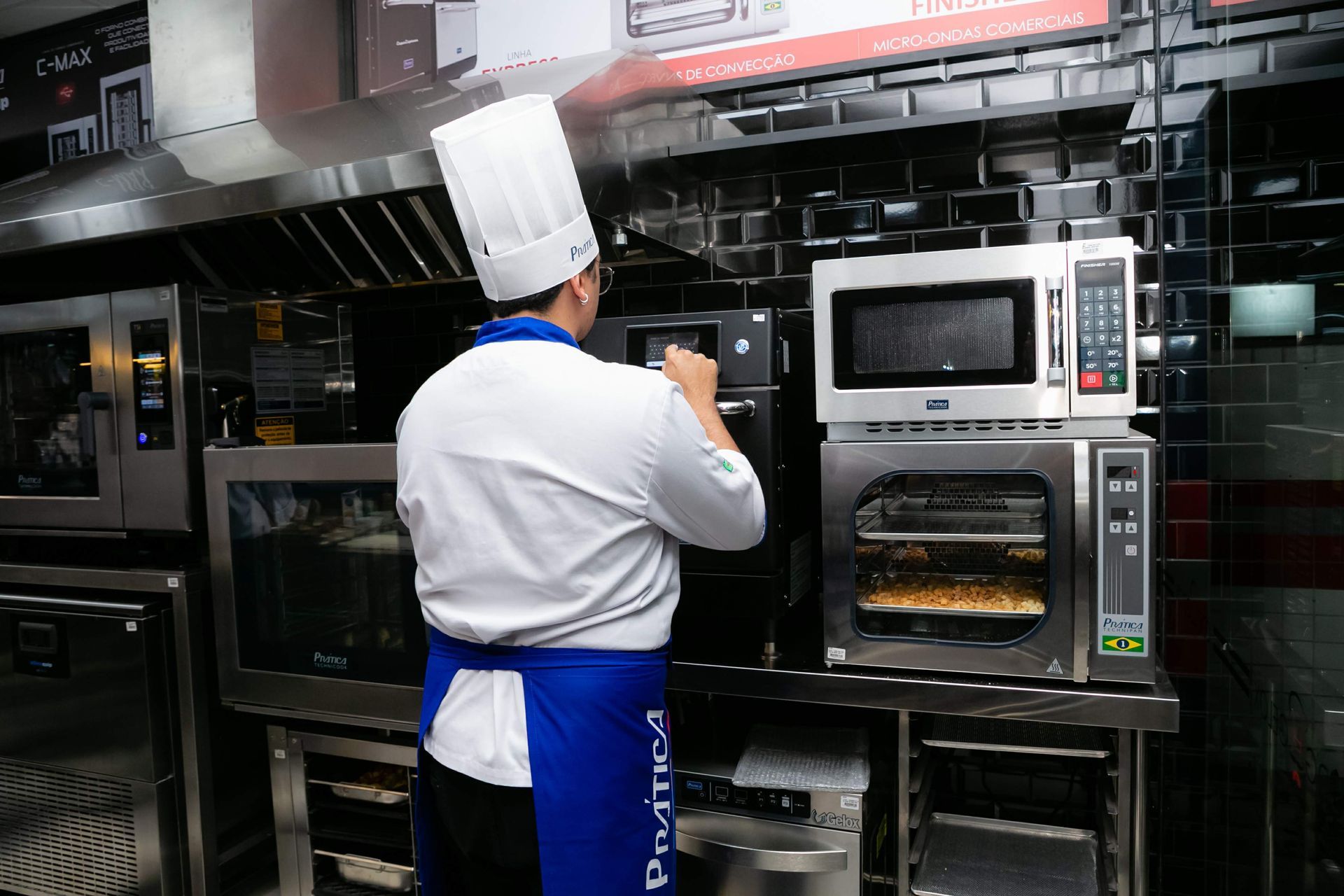 Um homem em uniforme de chef está olhando para um forno de micro-ondas.