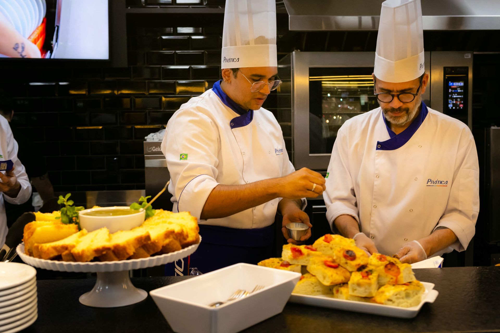 Dois chefs estão preparando comida em uma cozinha.