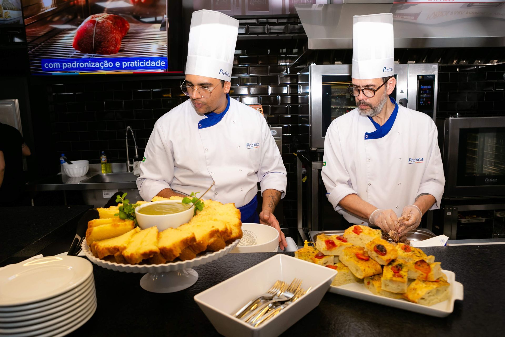 Dois chefs estão preparando comida em uma cozinha.