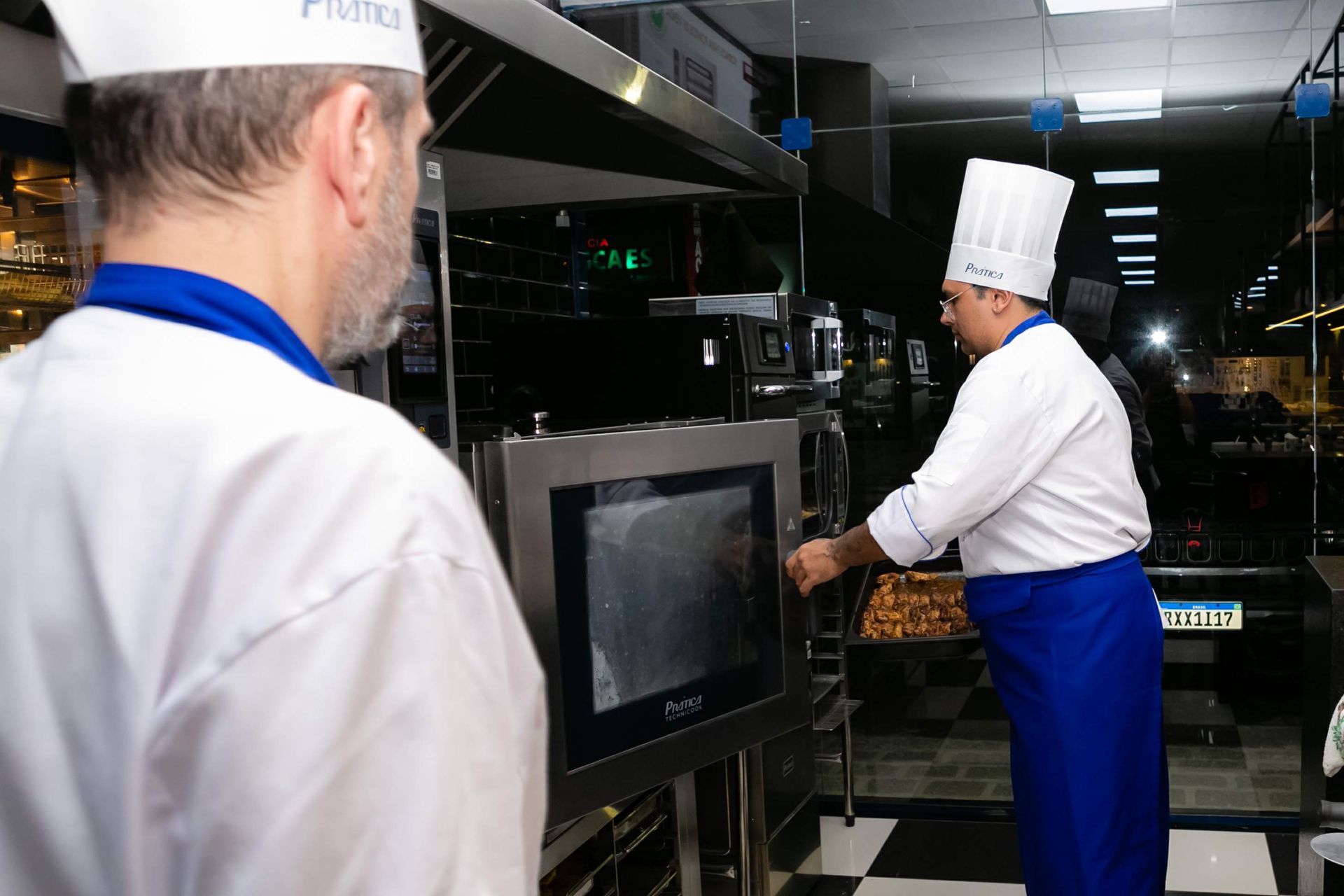 Um homem com chapéu de chef está olhando para uma tela em uma cozinha