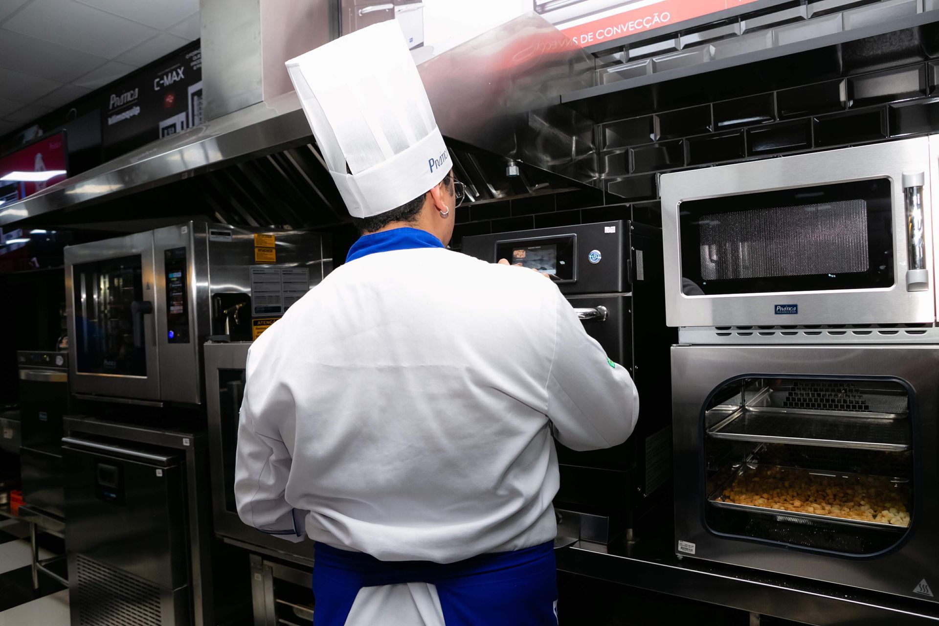 Um chef está em uma cozinha olhando para um forno de micro-ondas.