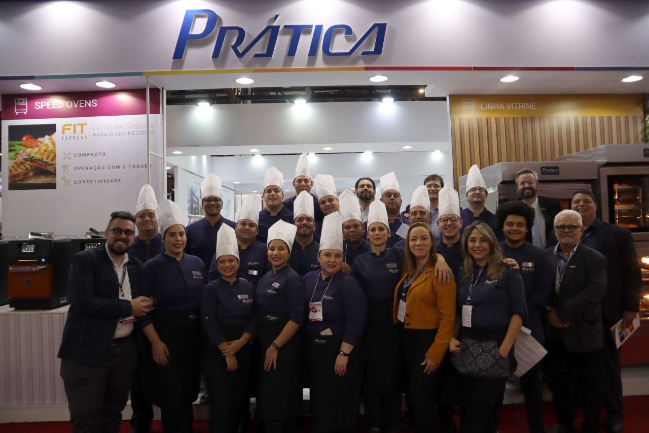 Um grupo de pessoas está posando para uma foto em frente a uma placa que diz prática.