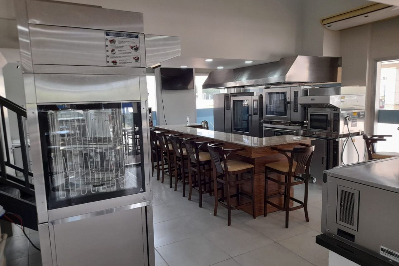 Uma cozinha com muitos eletrodomésticos e um balcão longo.