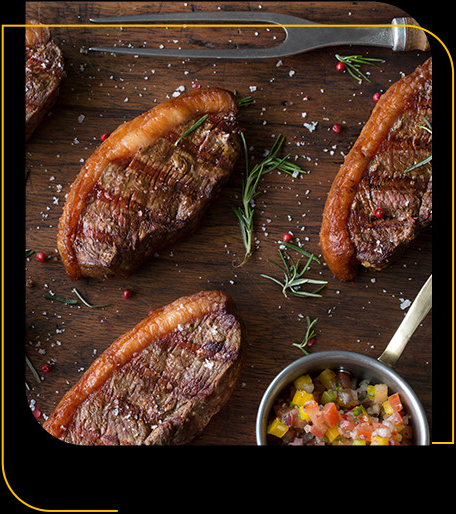 Uma mesa de madeira coberta com bifes e uma tigela de molho.