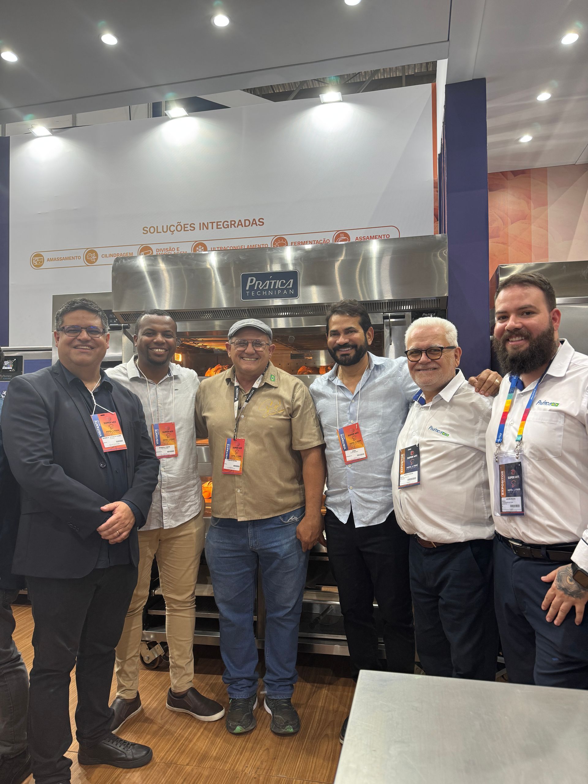 Grupo de pessoas em pé em frente a um forno industrial.