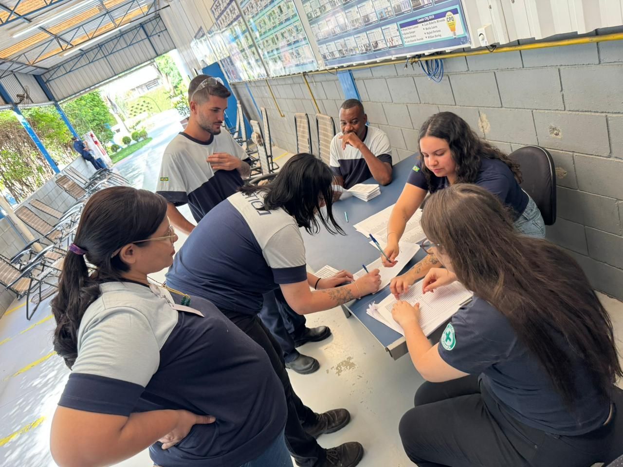 Grupo de pessoas revisando documentos em um ambiente fabril.