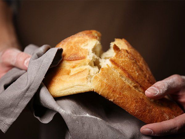 Uma pessoa está segurando um pedaço de pão com uma mordida.