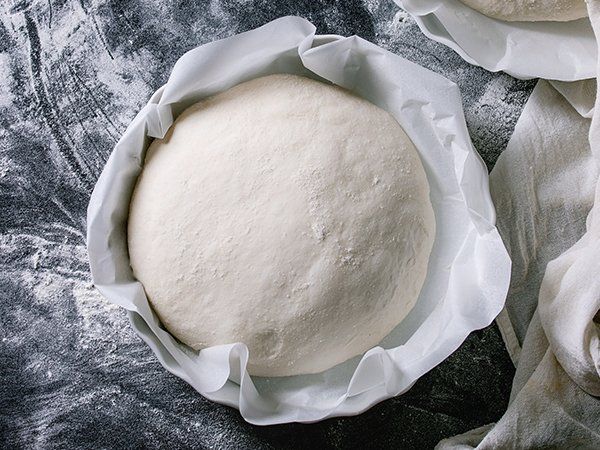 Uma bola de massa está embrulhada em papel manteiga sobre uma mesa.
