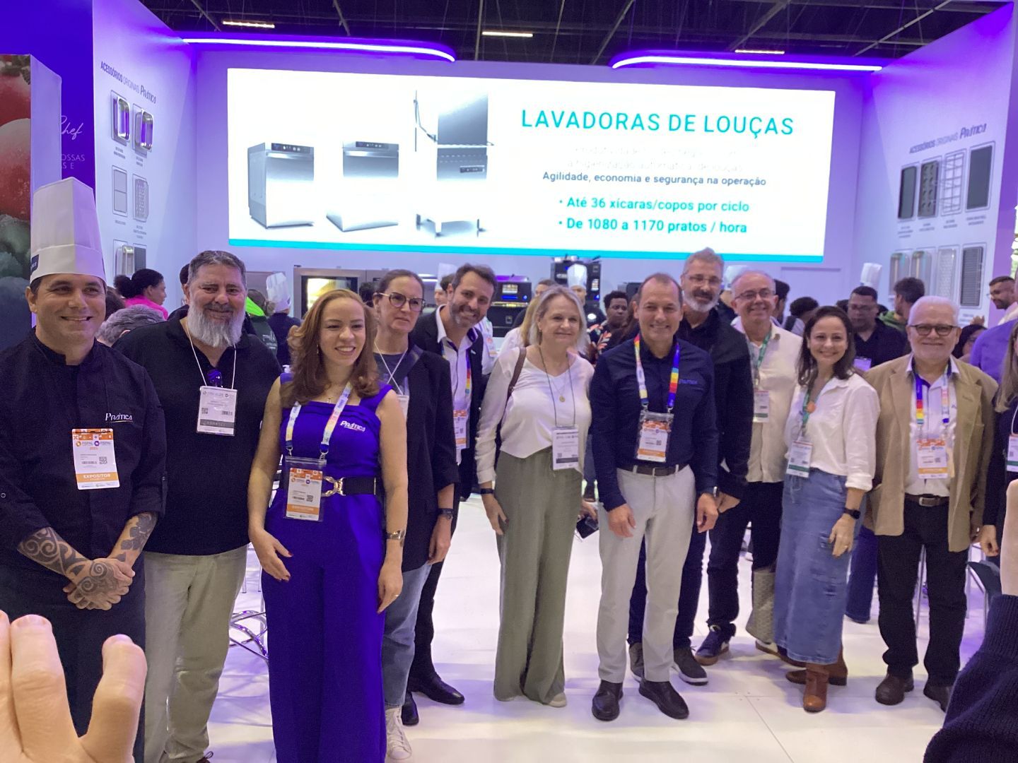 Um grupo de pessoas está posando para uma foto em frente a uma placa que diz lavadoras de loucas