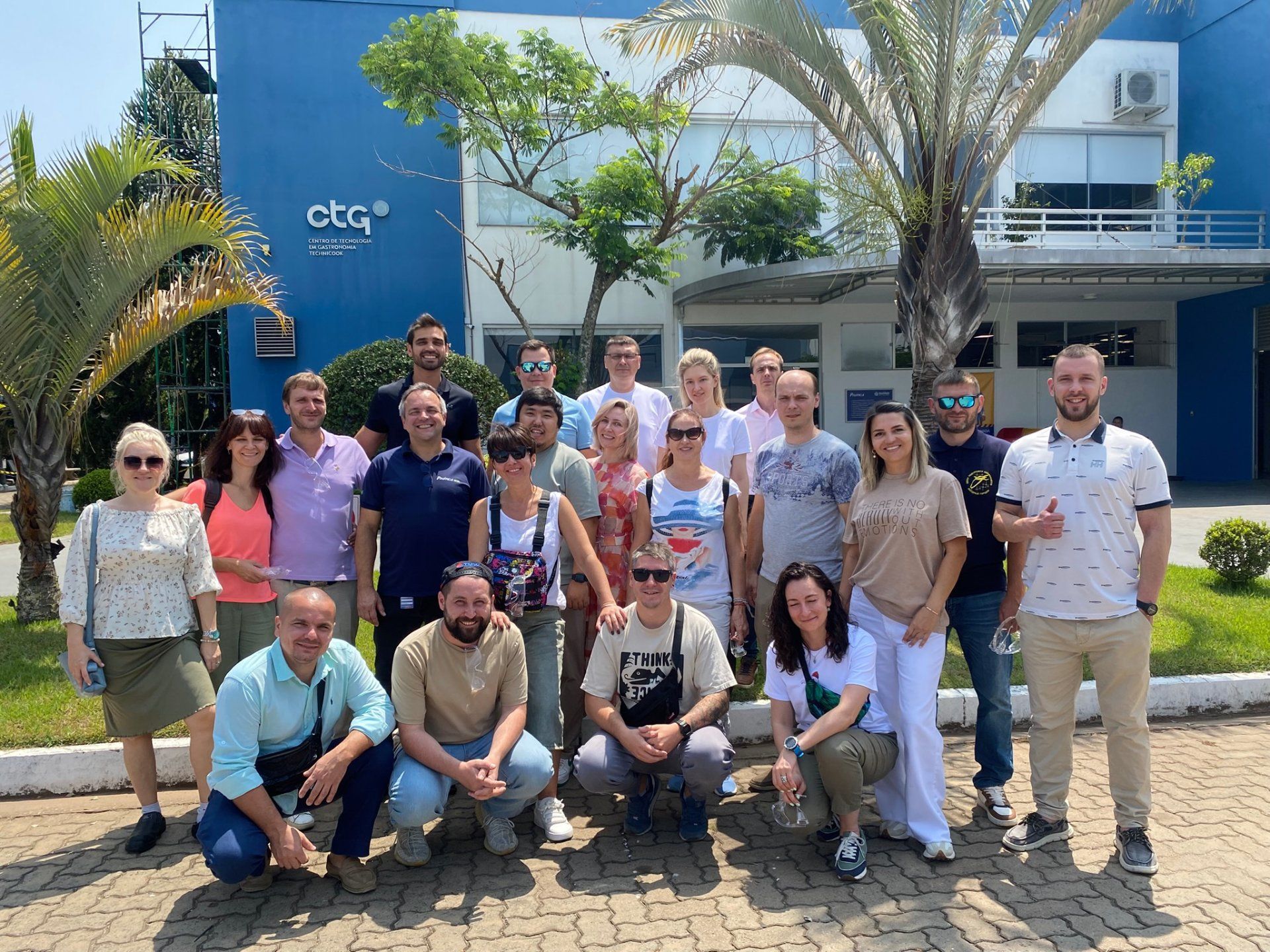 Um grupo de pessoas está posando para uma foto em frente a um prédio.