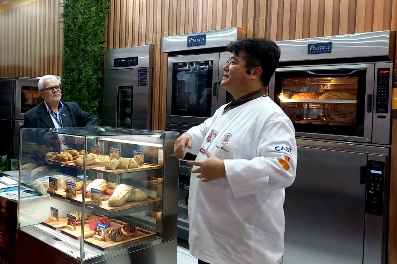 Um homem está parado em frente a uma vitrine em uma padaria.