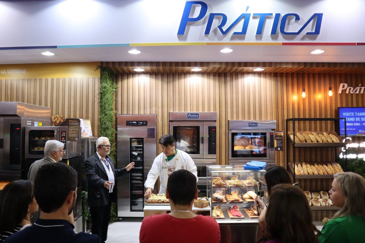 Um grupo de pessoas em pé na frente de uma padaria chamada pratica
