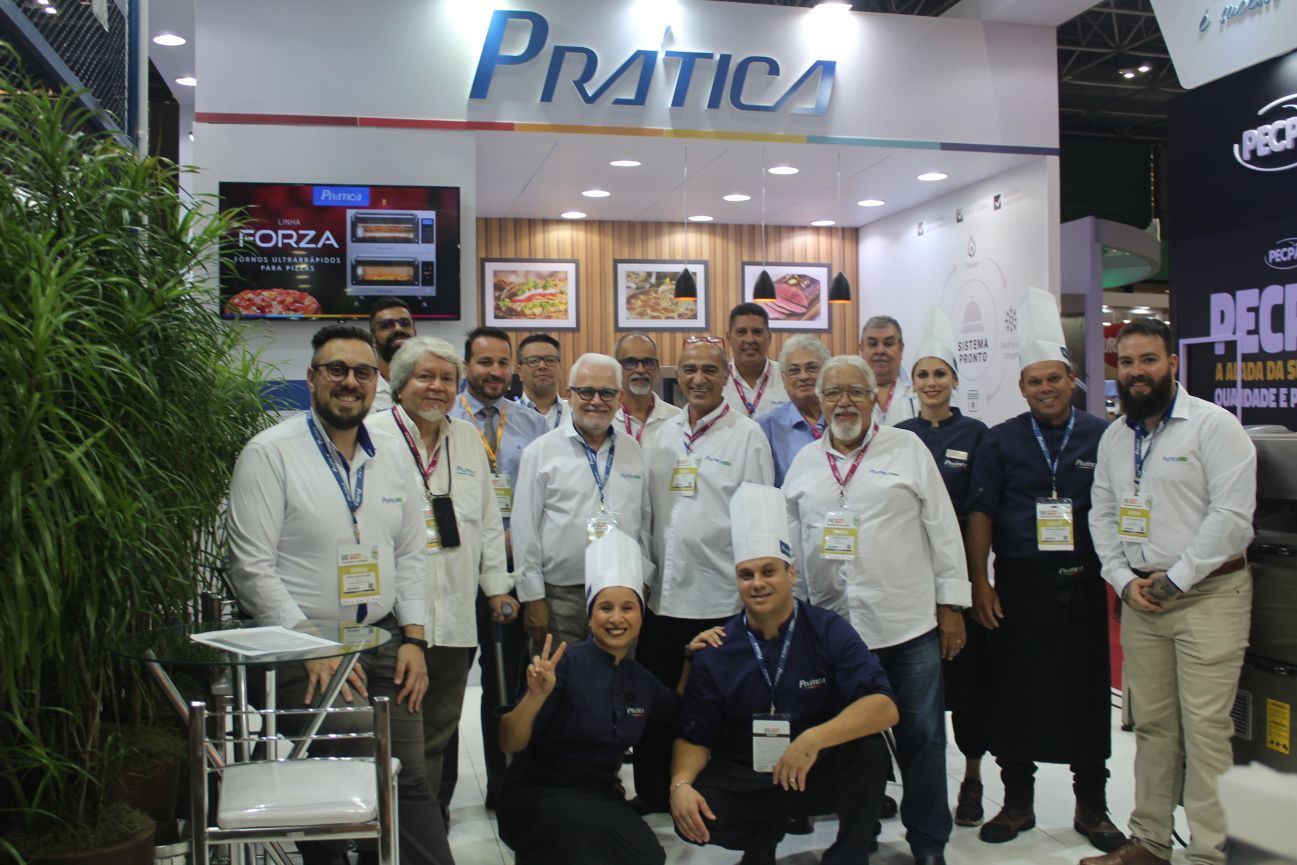 Um grupo de pessoas posa para uma foto em frente a uma placa que diz pratica.