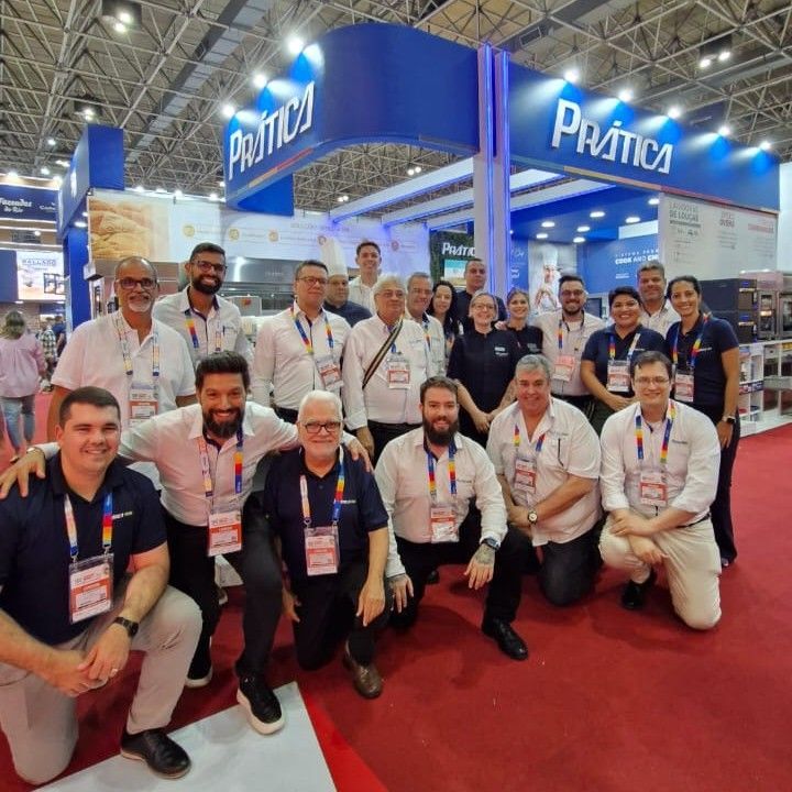 Um grupo de pessoas posando para uma foto em frente a uma placa que diz pratica