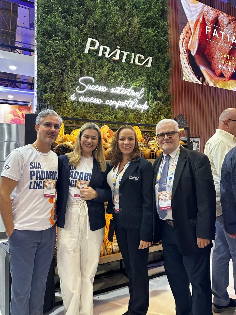Um grupo de pessoas está posando para uma foto em frente a uma placa.