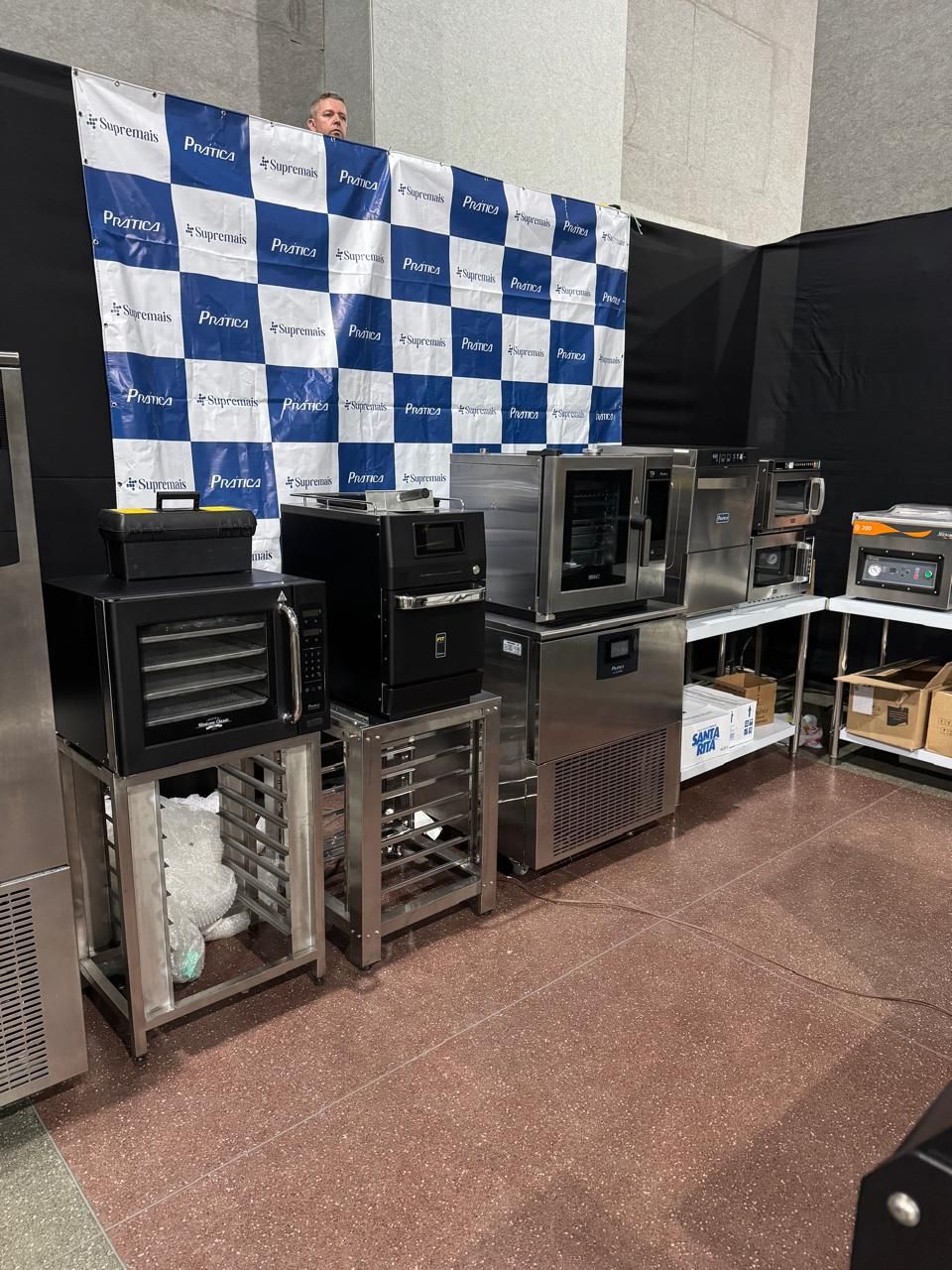Uma exposição de eletrodomésticos de cozinha comerciais em um fundo xadrez azul e branco.