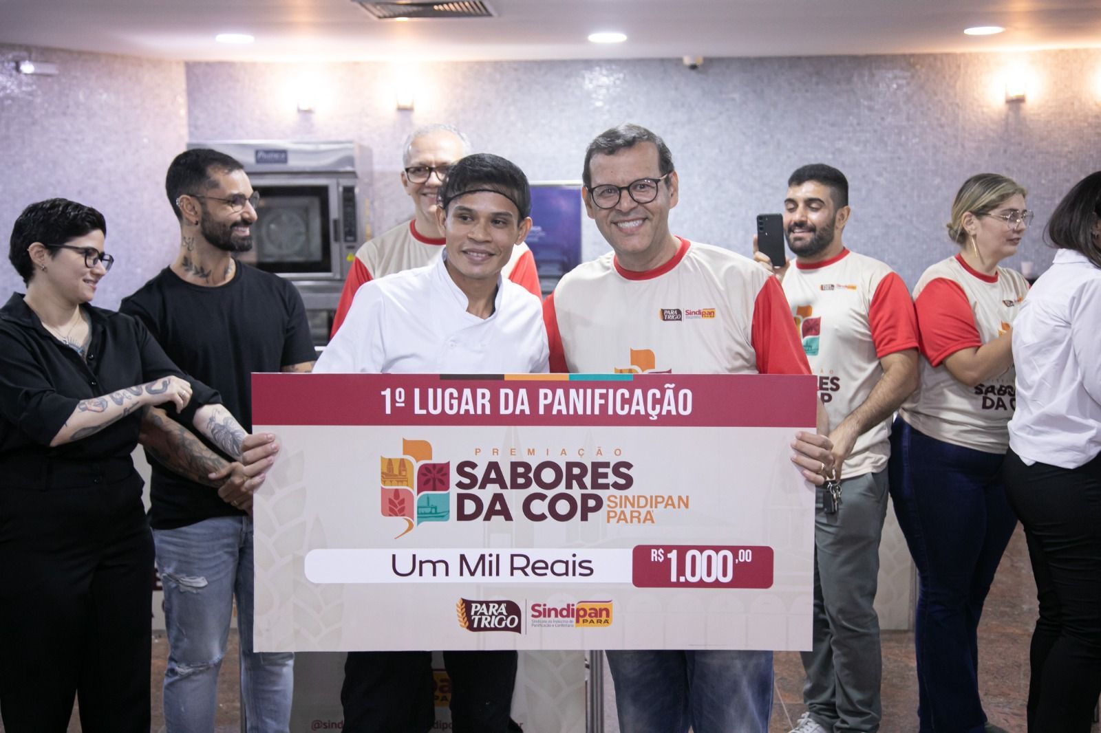 Pessoas segurando um cheque de grande valor referente ao 