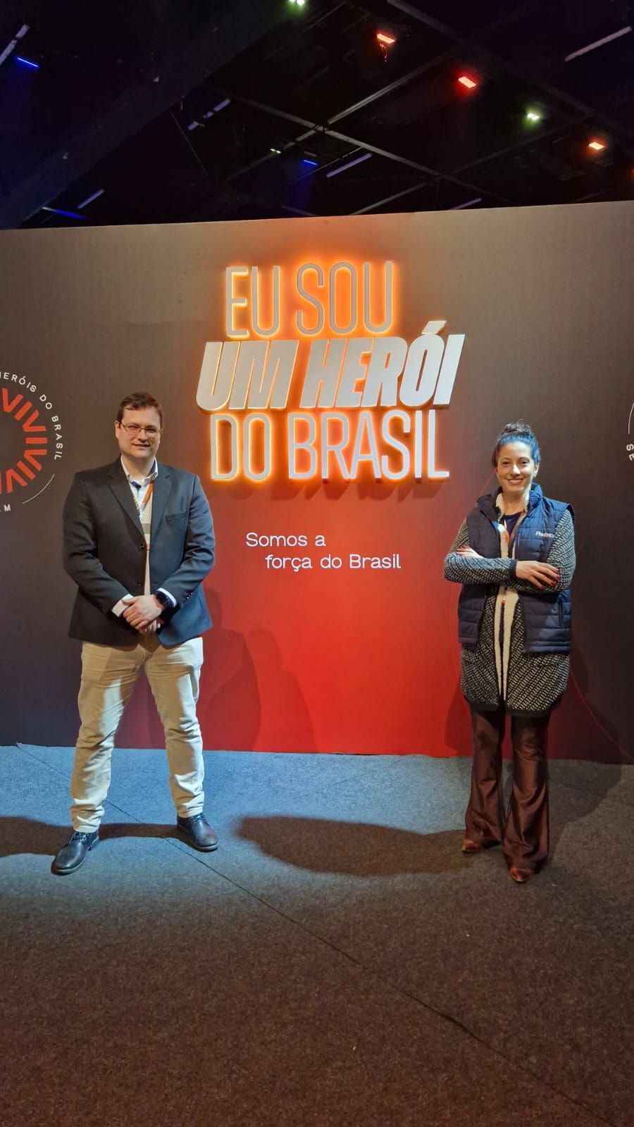 Duas pessoas estão em frente a uma placa que diz