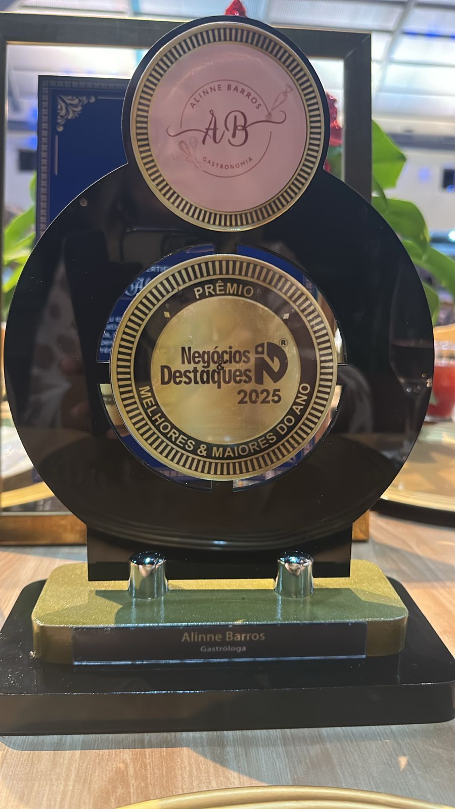 Troféu de premiação com detalhes em dourado, preto e rosa, possivelmente para