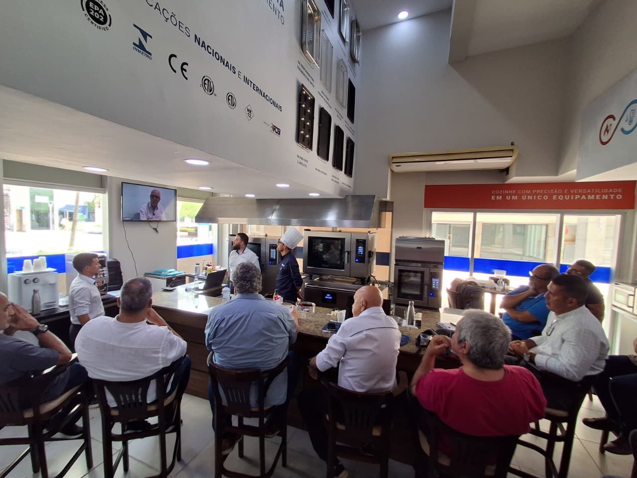 Grupo de homens em um balcão, assistindo a uma demonstração em uma loja de eletrodomésticos.