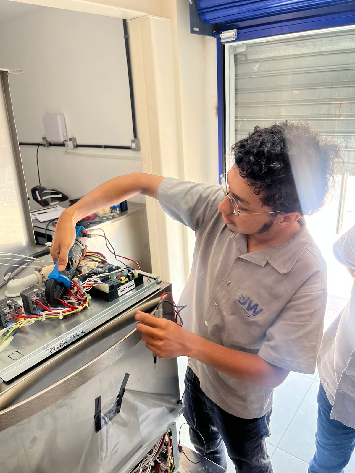 Homem de camisa cinza trabalhando em componentes eletrônicos.