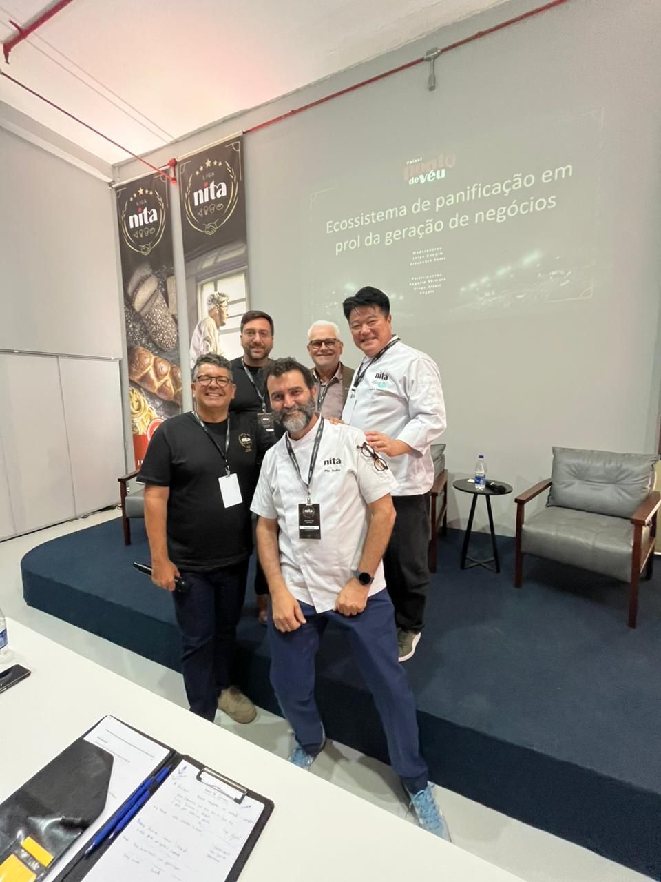 Um grupo de cinco pessoas está em um palco durante um evento