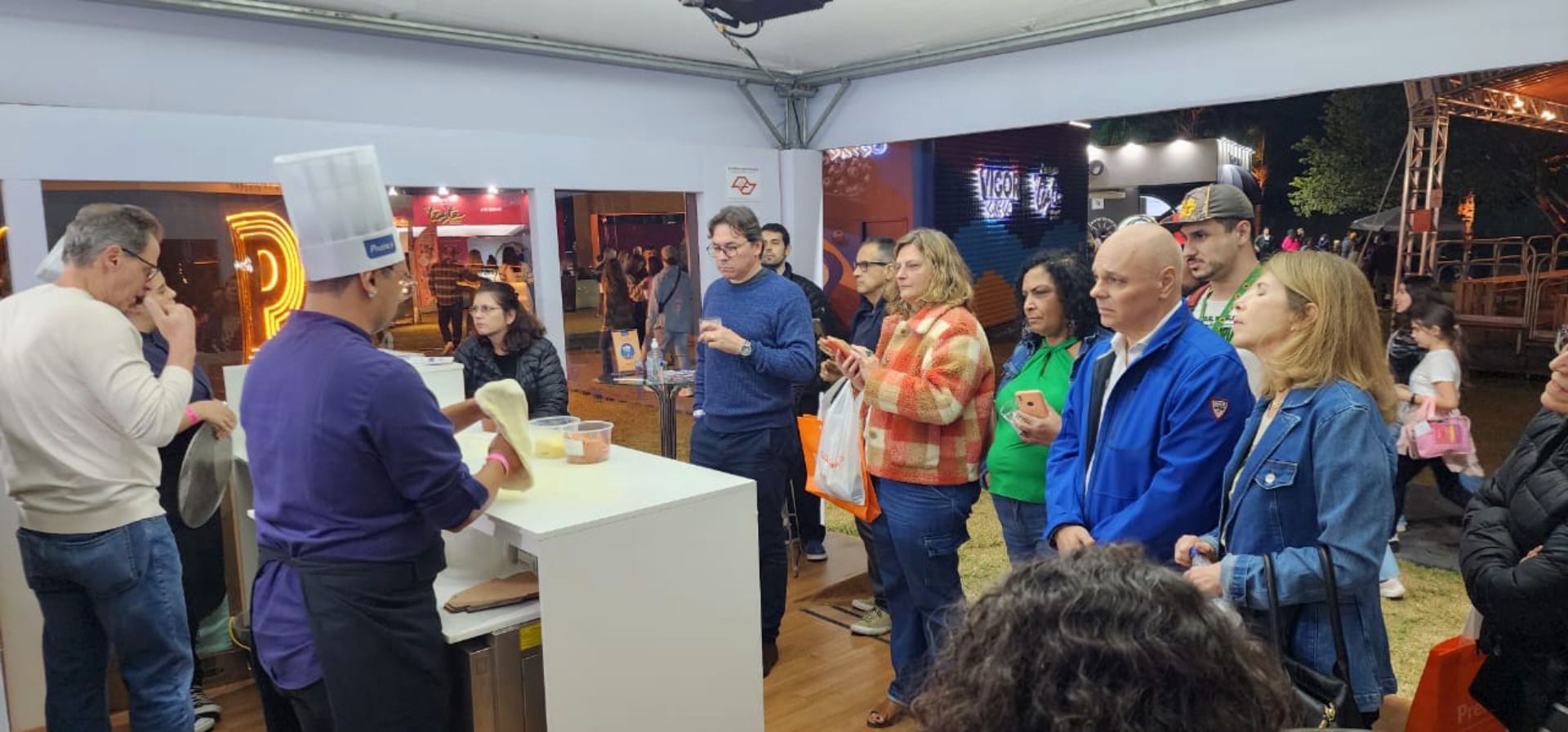 Um grupo de pessoas está em pé ao redor de uma mesa em uma sala.