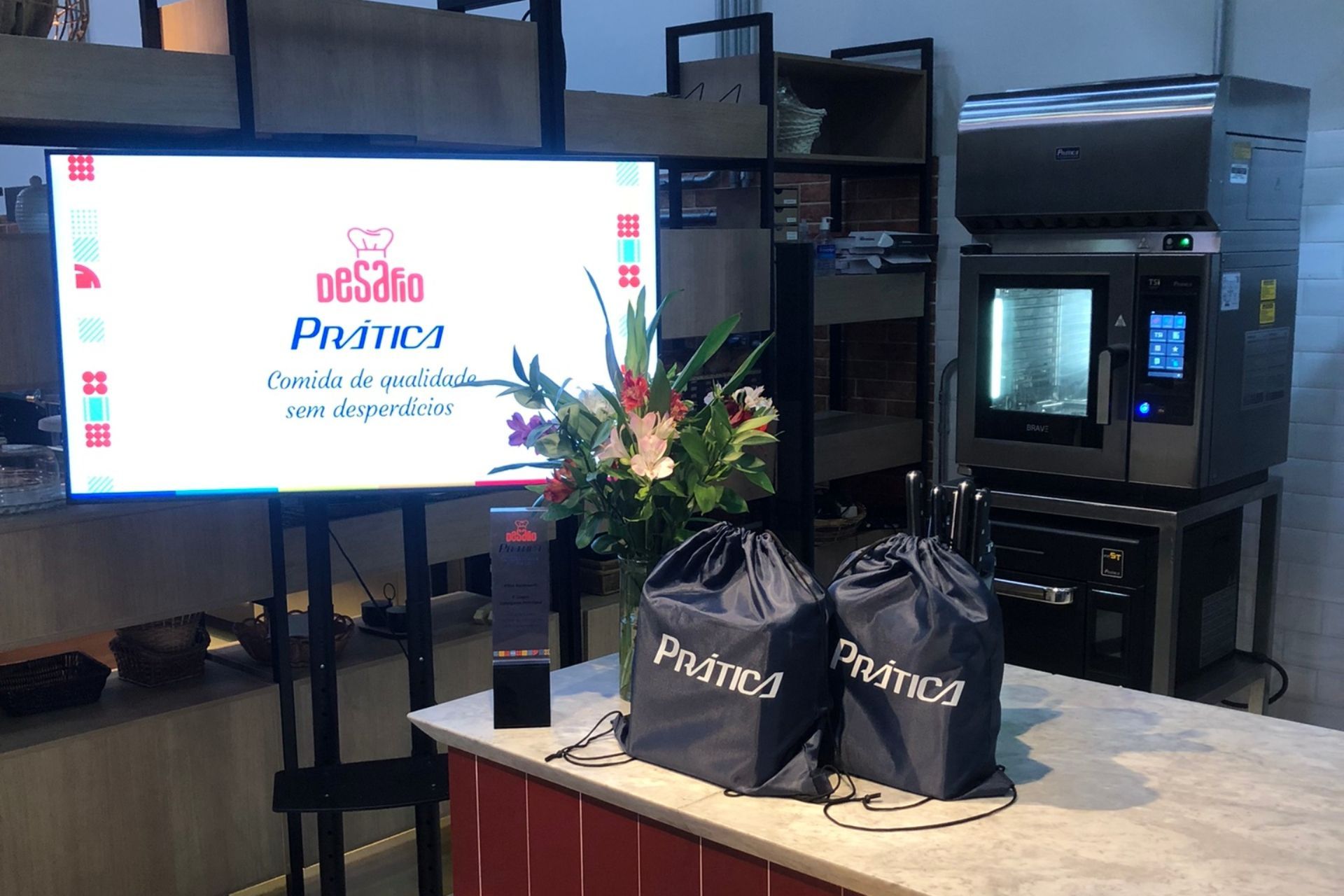 Evento de inauguração do restaurante: placa, sacolas, flores e forno industrial.