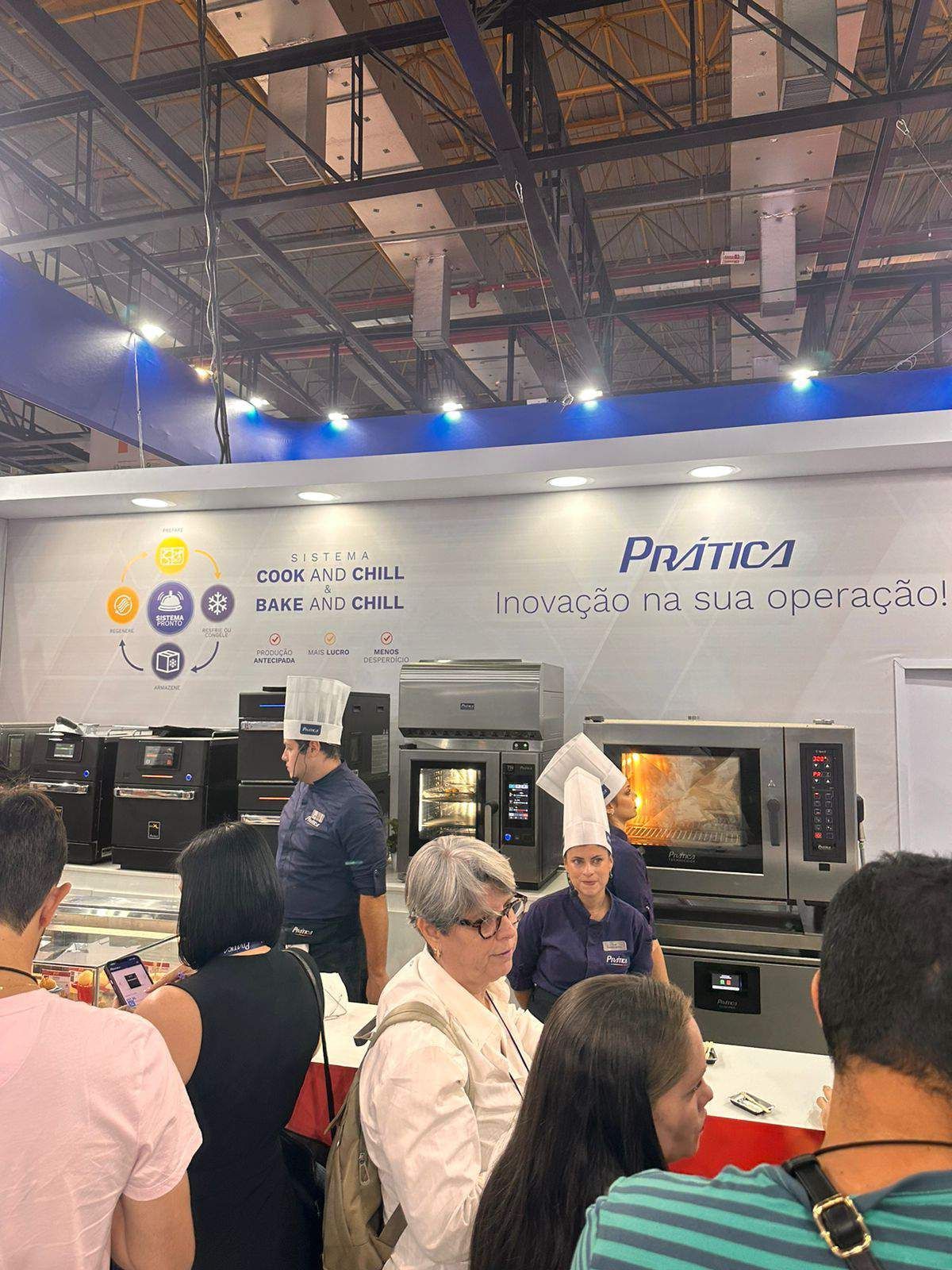 Um grupo de pessoas está em frente a uma exposição de equipamentos de cozinha.
