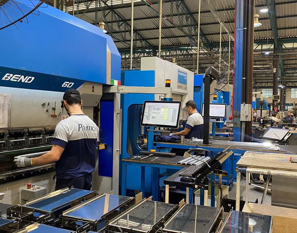 Dois homens estão trabalhando em uma máquina em uma fábrica.
