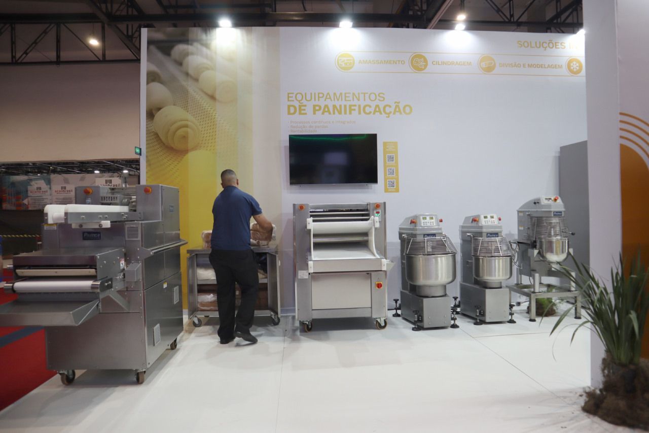 Um homem está em pé em frente a uma exposição de equipamentos de padaria.