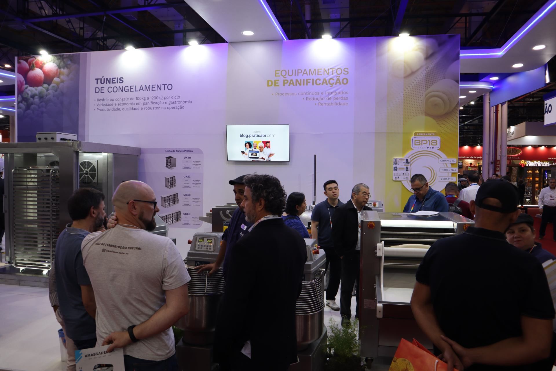 Um grupo de pessoas está em volta de um estande em uma convenção.