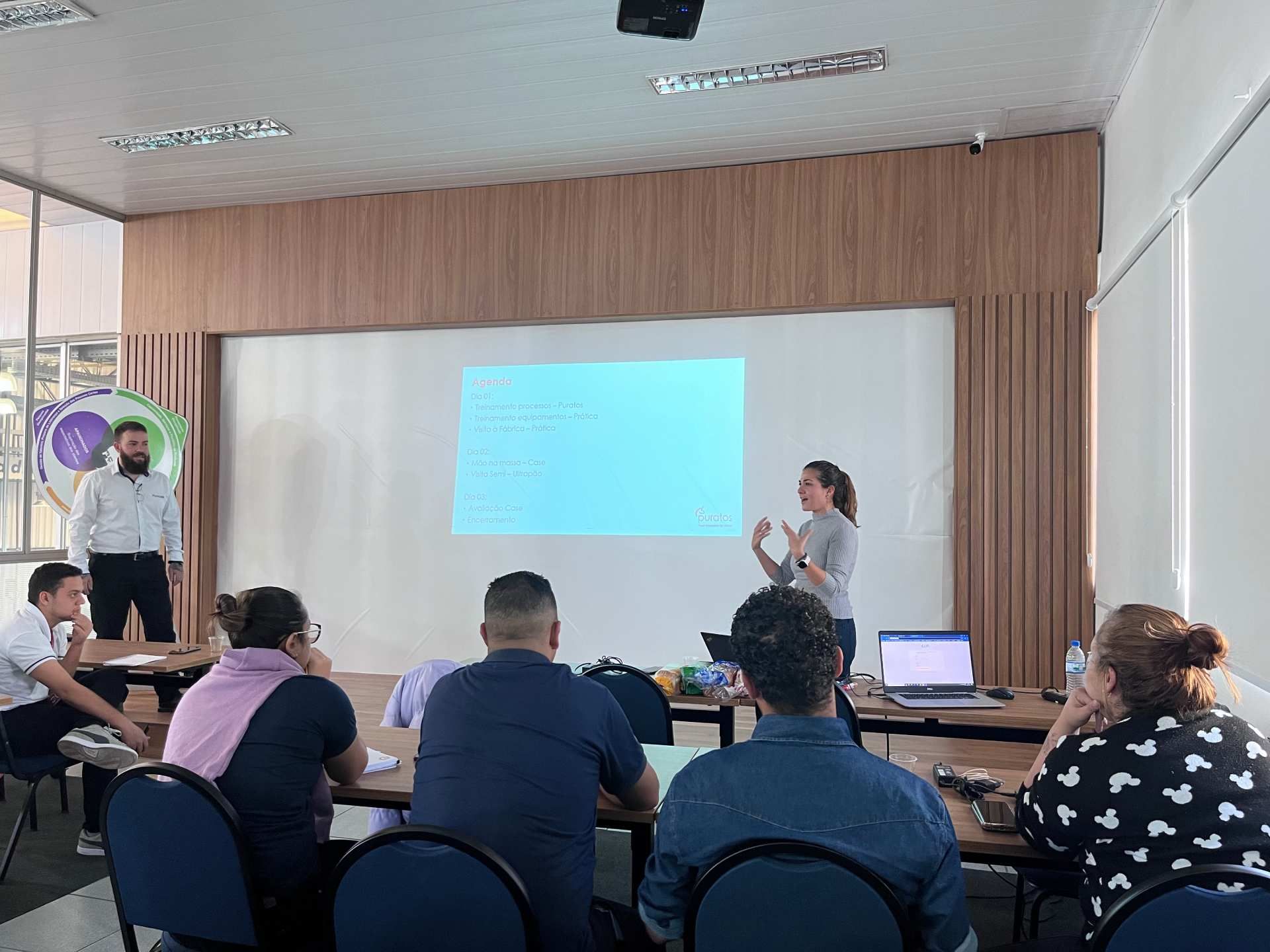 Uma mulher está fazendo uma apresentação para um grupo de pessoas em uma sala de conferências.