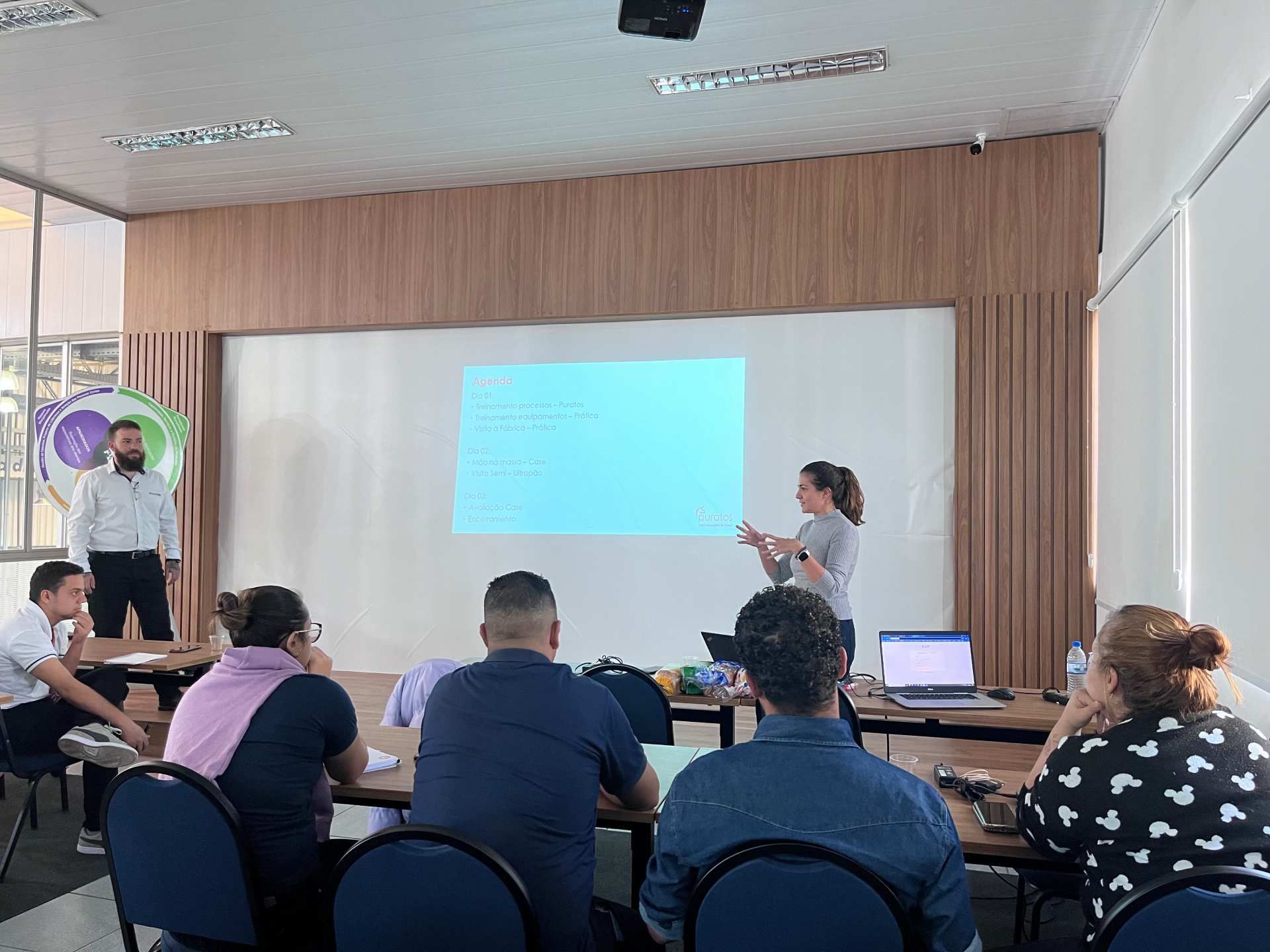 Uma mulher está fazendo uma apresentação para um grupo de pessoas em uma sala de conferências.