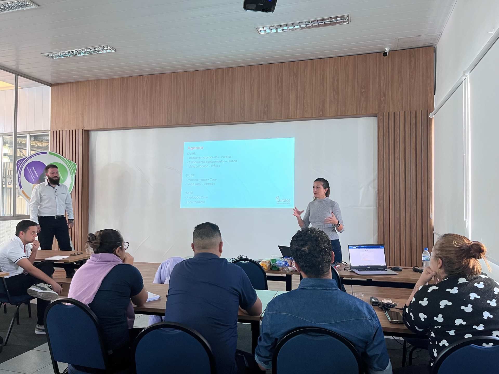 Uma mulher está fazendo uma apresentação para um grupo de pessoas em uma sala de conferências.