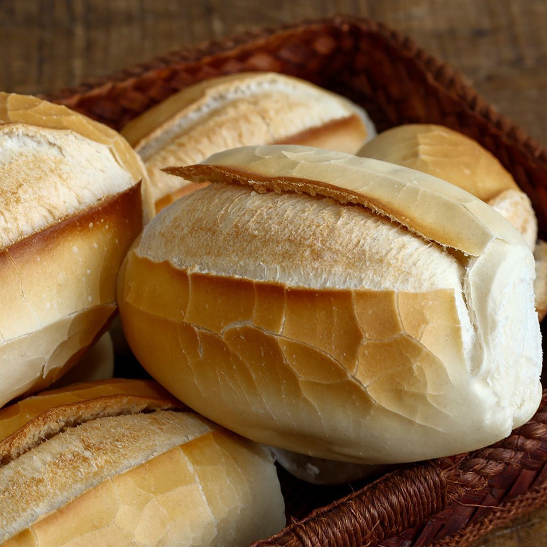 Uma cesta cheia de pãezinhos sobre uma mesa de madeira