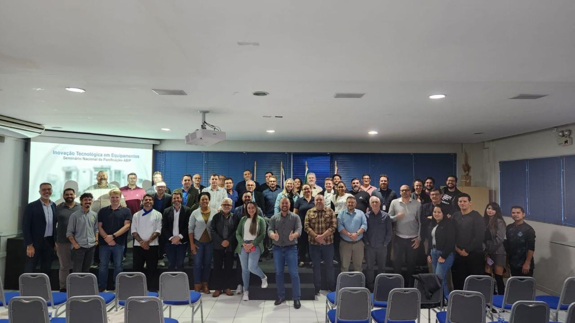 Um grupo de pessoas está posando para uma foto em uma sala de conferências.
