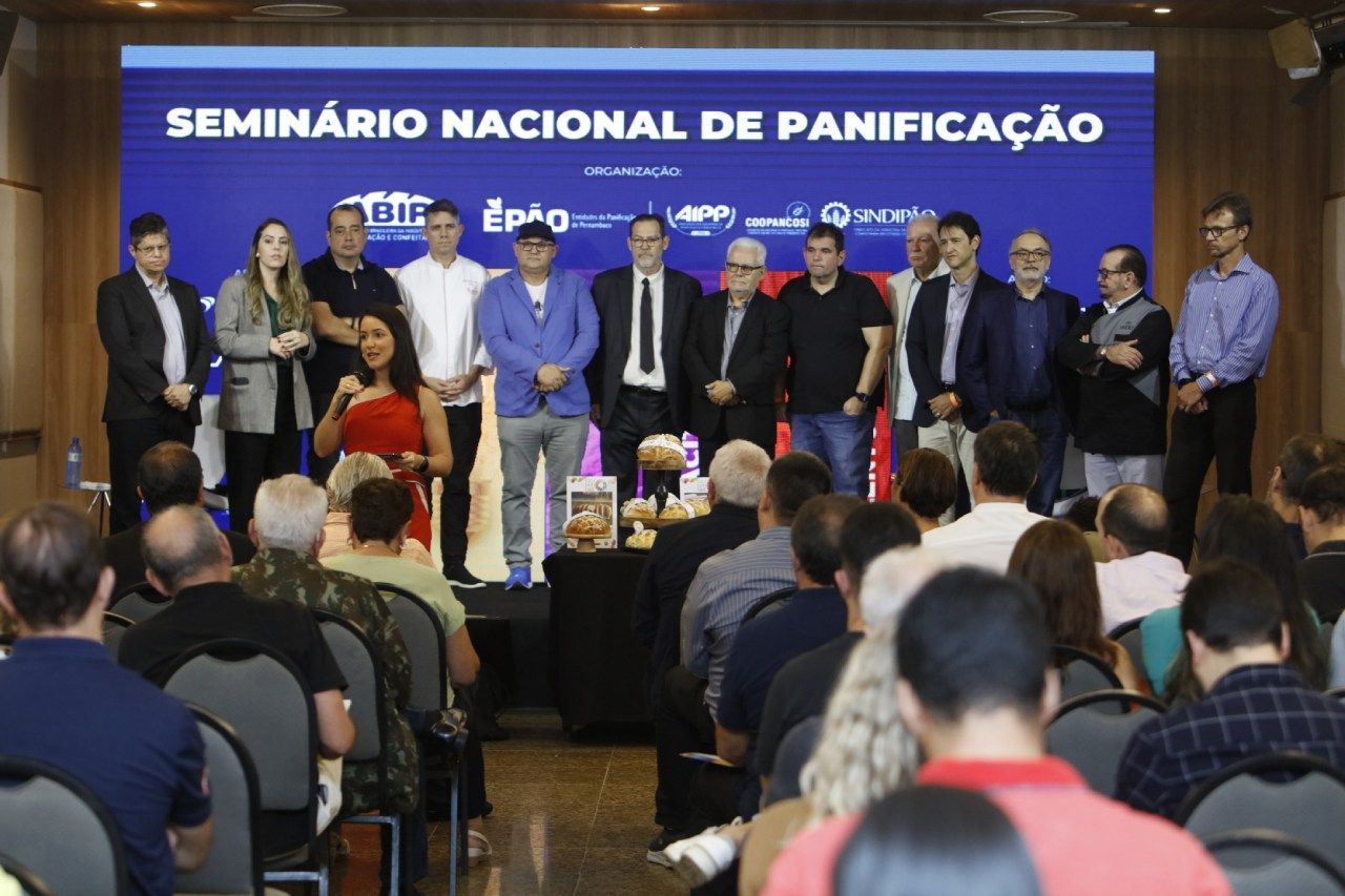 A group of people standing in front of a sign that says seminario nacional de panificação