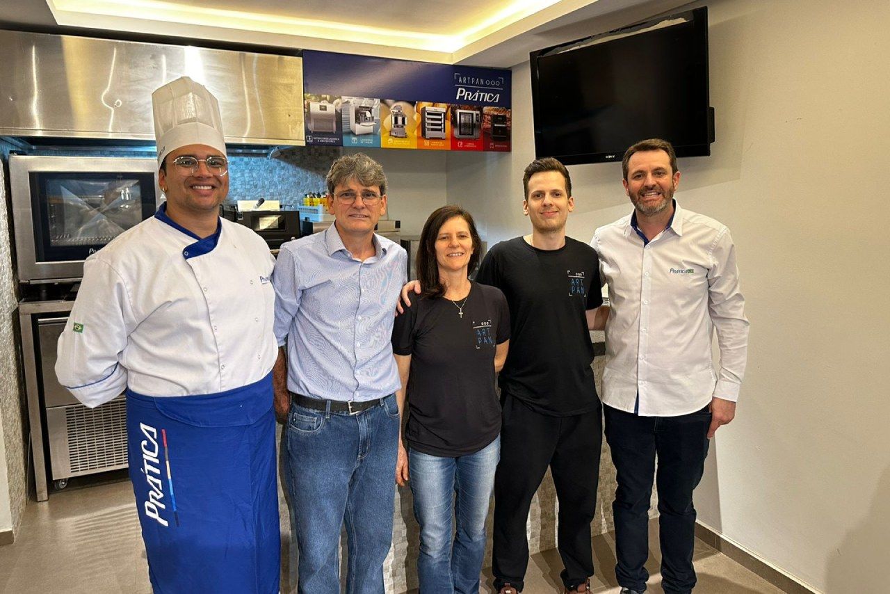 Um grupo de pessoas está posando para uma foto em uma cozinha.