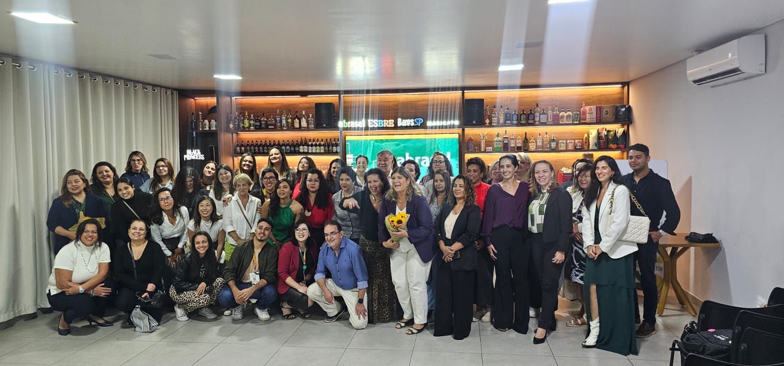 Um grande grupo de pessoas está posando para uma foto em uma sala.