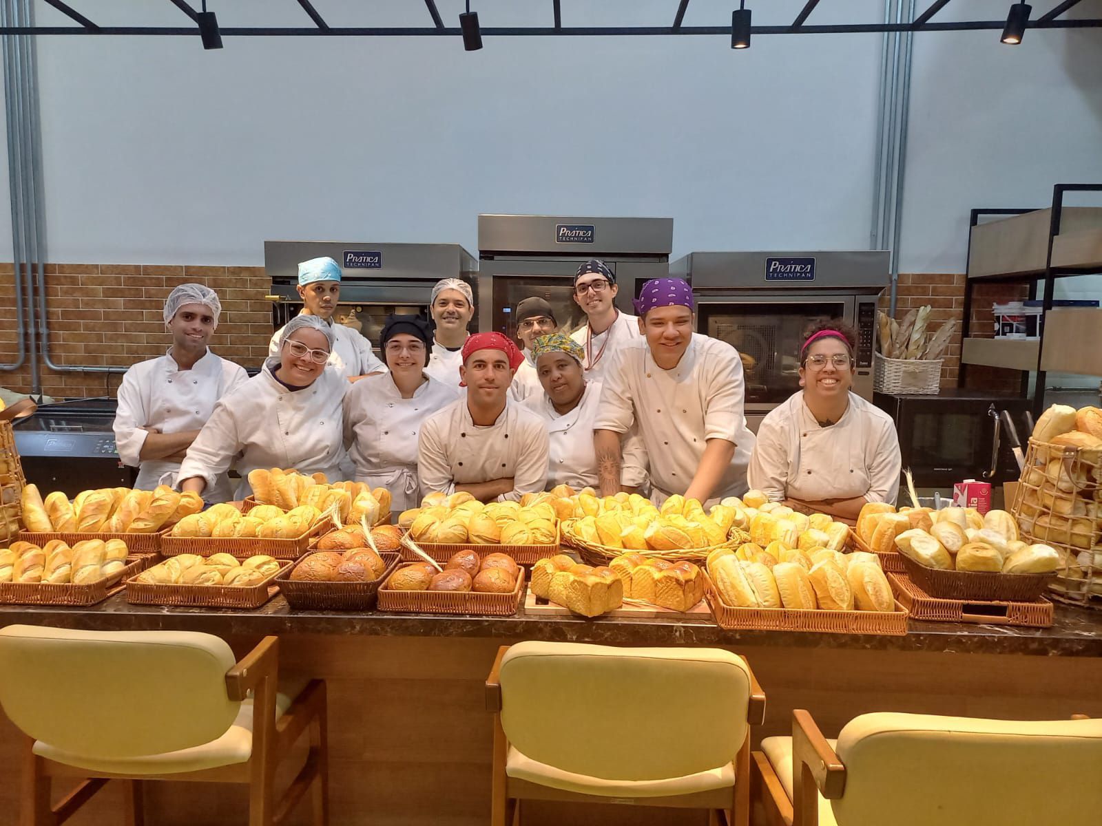 Um grupo de pessoas está posando para uma foto em uma padaria.