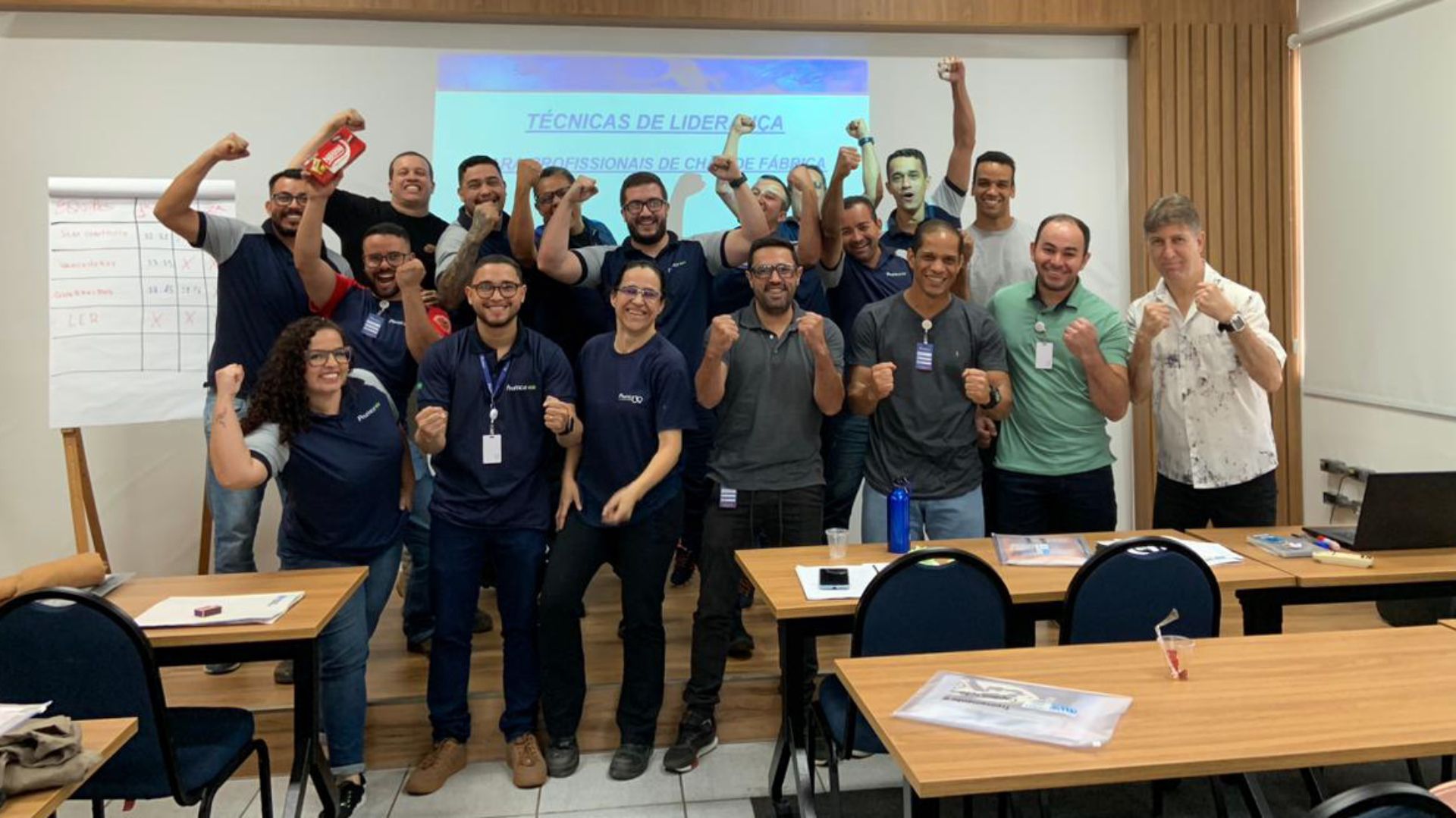 Um grupo de pessoas está posando para uma foto em uma sala de aula.