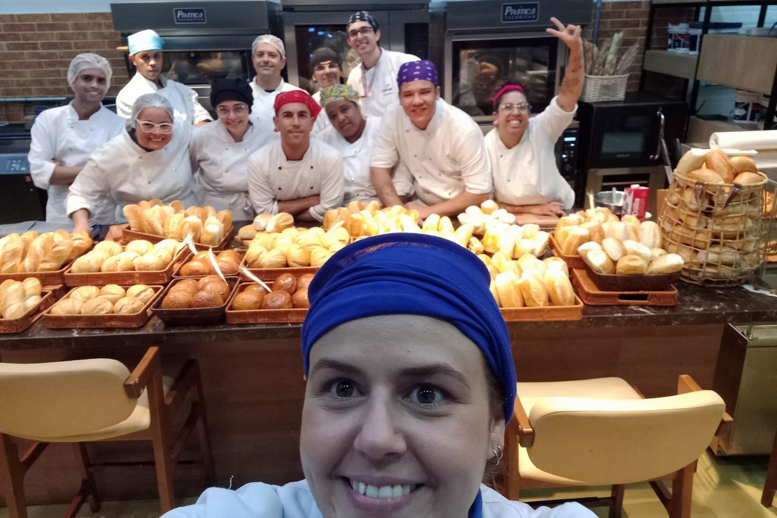 Um grupo de pessoas está posando para uma foto em uma padaria