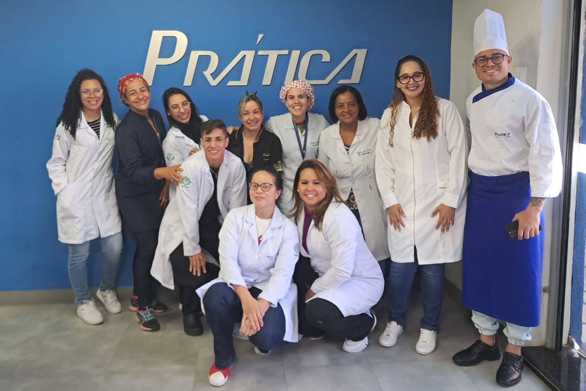 Um grupo de pessoas posando para uma foto em frente a uma placa que diz pratica