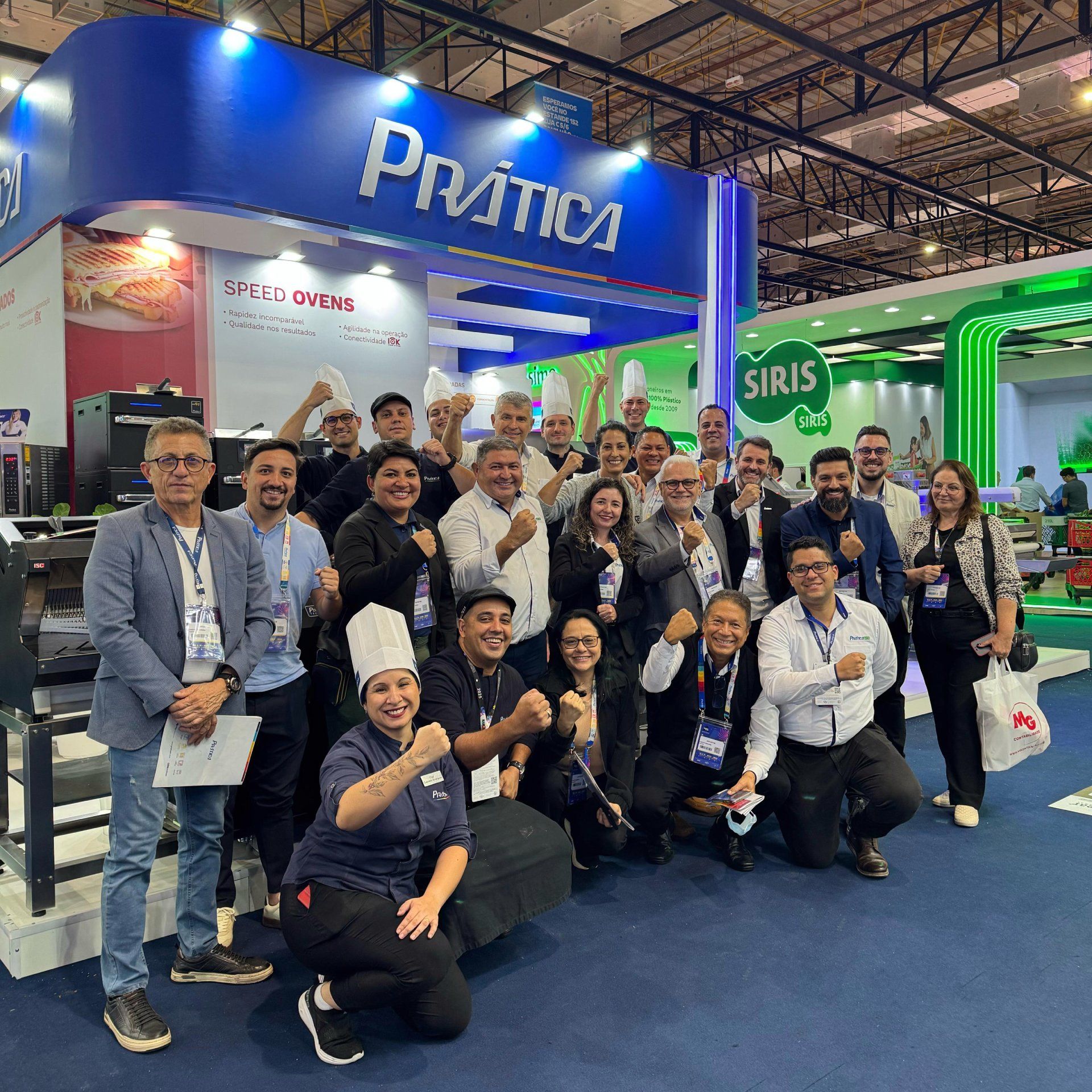 Um grupo de pessoas está posando para uma foto em frente a uma cabine de prática.