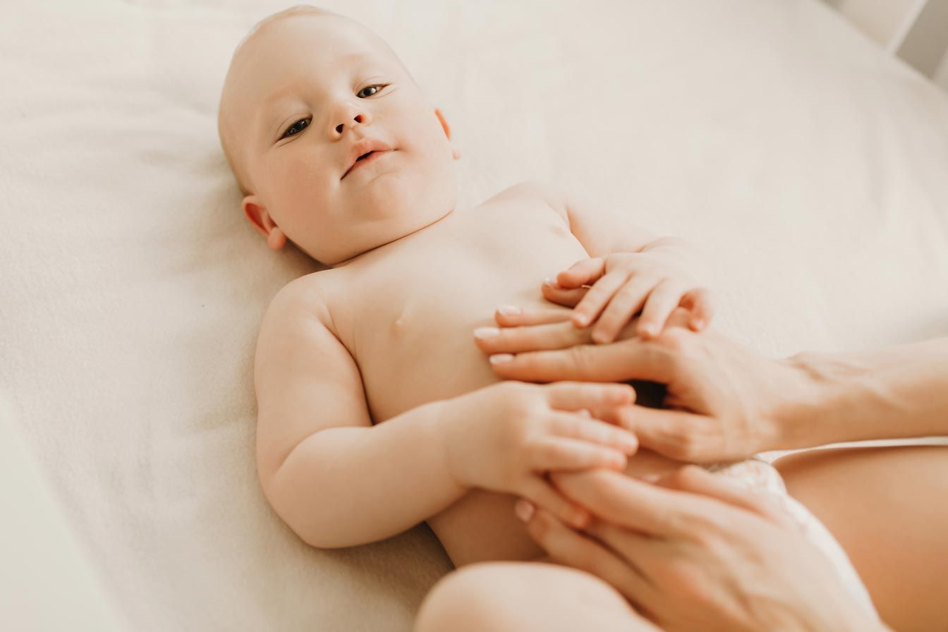 A woman is holding a baby in her arms on a bed.