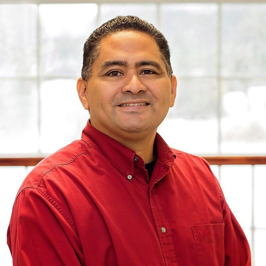 A man in a red shirt is smiling for the camera