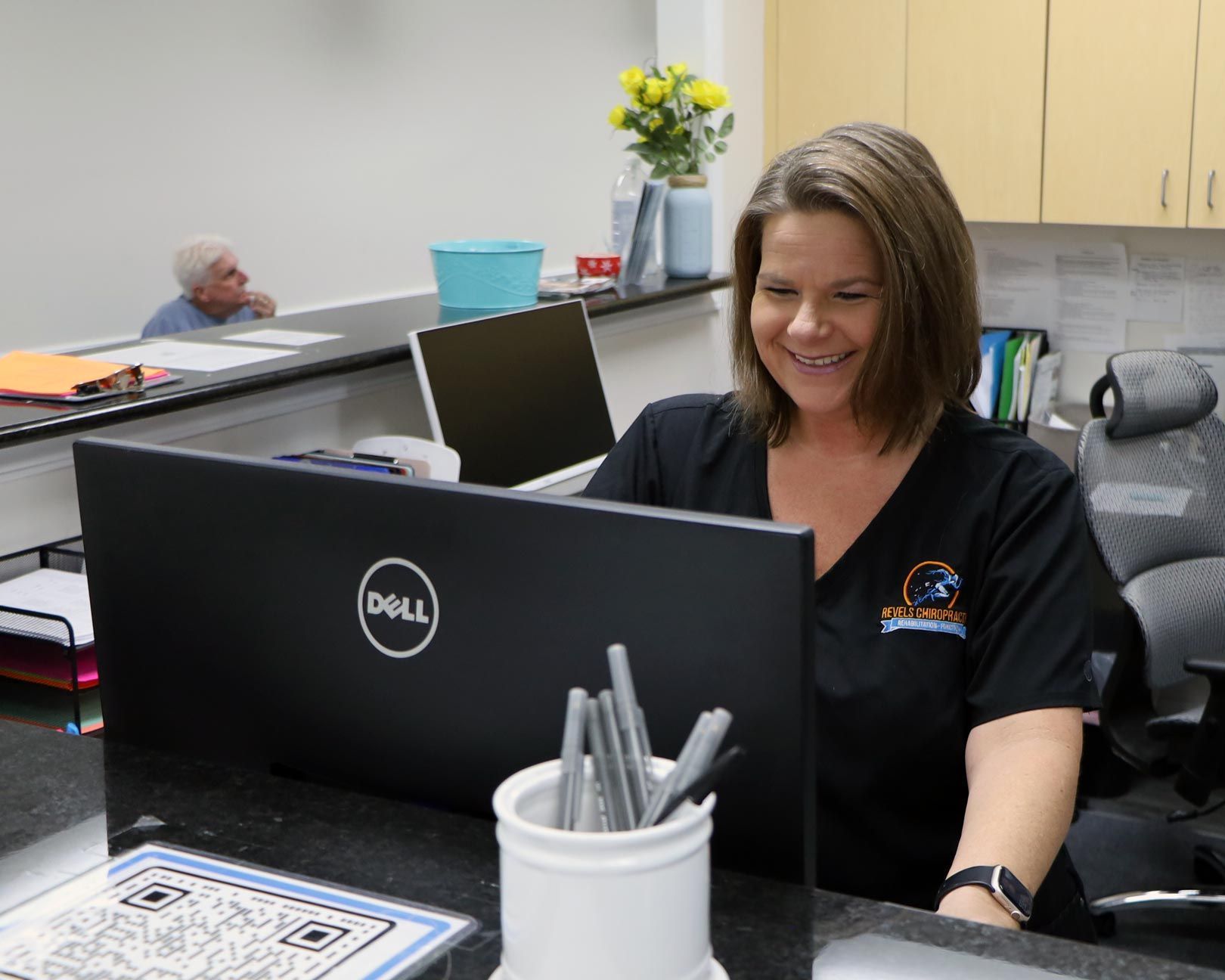 A woman is sitting in front of a dell laptop computer.